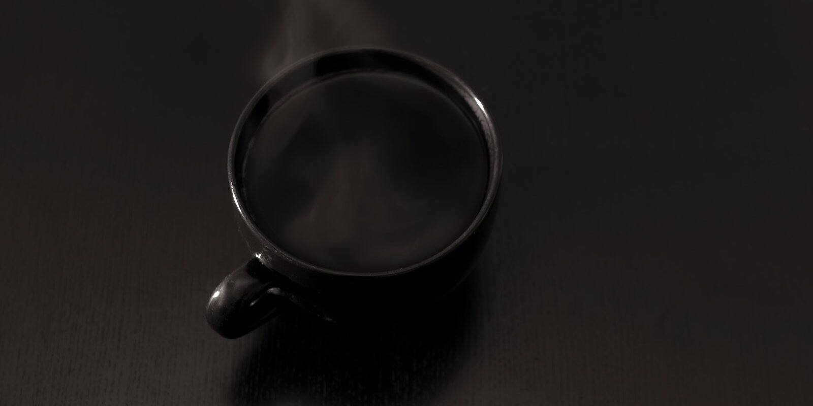 Taza de café humeante sobre una superficie oscura