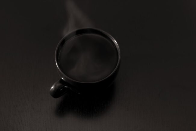 Taza de café humeante sobre una superficie oscura