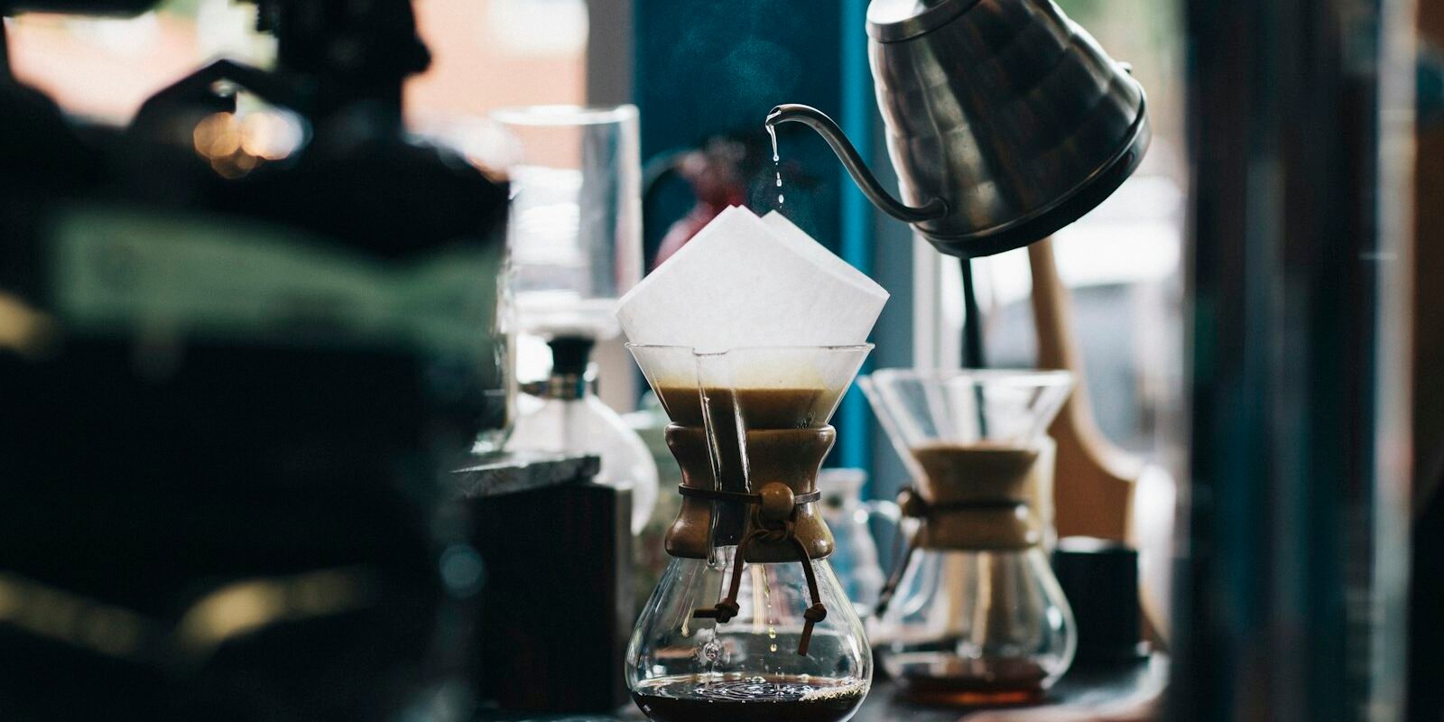 Café de filtro o soluble: qué vio un estudio sobre envejecimiento Persona vertiendo agua caliente en una cafetera de filtro de vidrio para preparar café