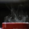 Taza de café humeante recién servida sobre una mesa, con vapor saliendo de la bebida caliente