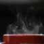 Taza de café humeante recién servida sobre una mesa, con vapor saliendo de la bebida caliente