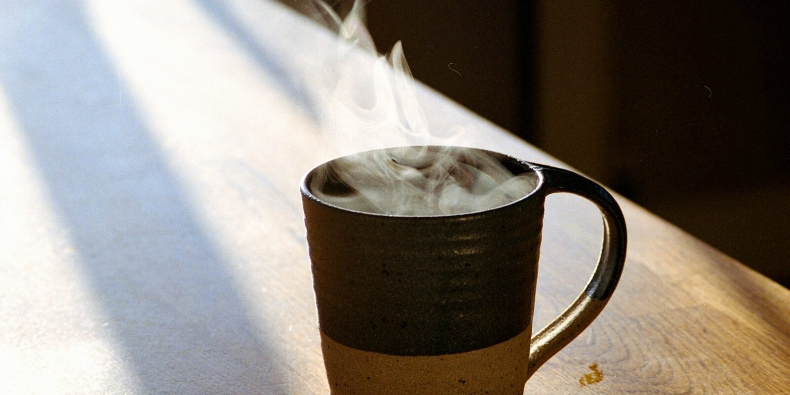 Café por la mañana y resistencia a la insulina: lo que vio un estudio Taza de café humeante sobre una mesa de madera iluminada por la luz de la mañana