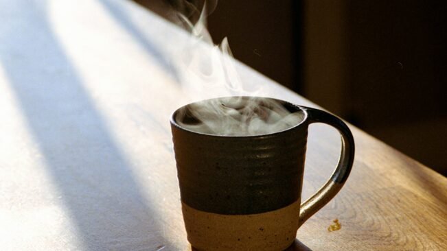 Café por la mañana y resistencia a la insulina: lo que vio un estudio Taza de café humeante sobre una mesa de madera iluminada por la luz de la mañana