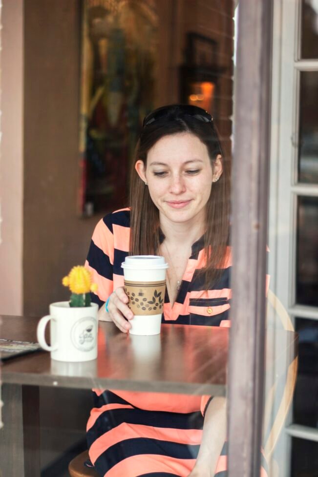 Café y migraña: qué dice una revisión de 19 estudios sobre la cafeína Mujer sentada a una mesa mirando la taza de café que sostiene en la mano