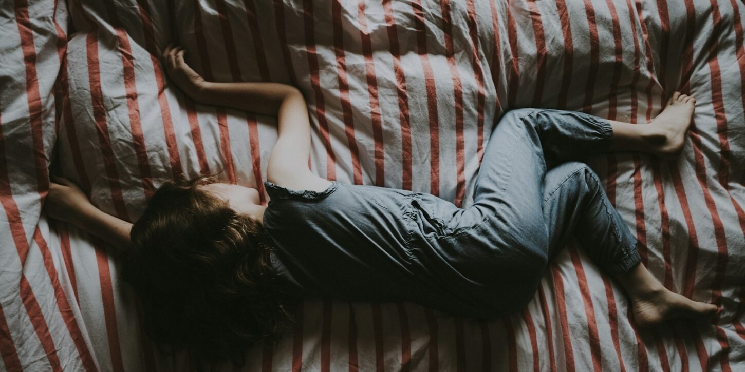 Cafeína en niños: ligada a dormir menos y a diferencias en el cerebro Niño dormido en una cama con sábanas rojas y grises