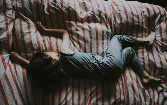 Cafeína en niños: ligada a dormir menos y a diferencias en el cerebro Niño dormido en una cama con sábanas rojas y grises