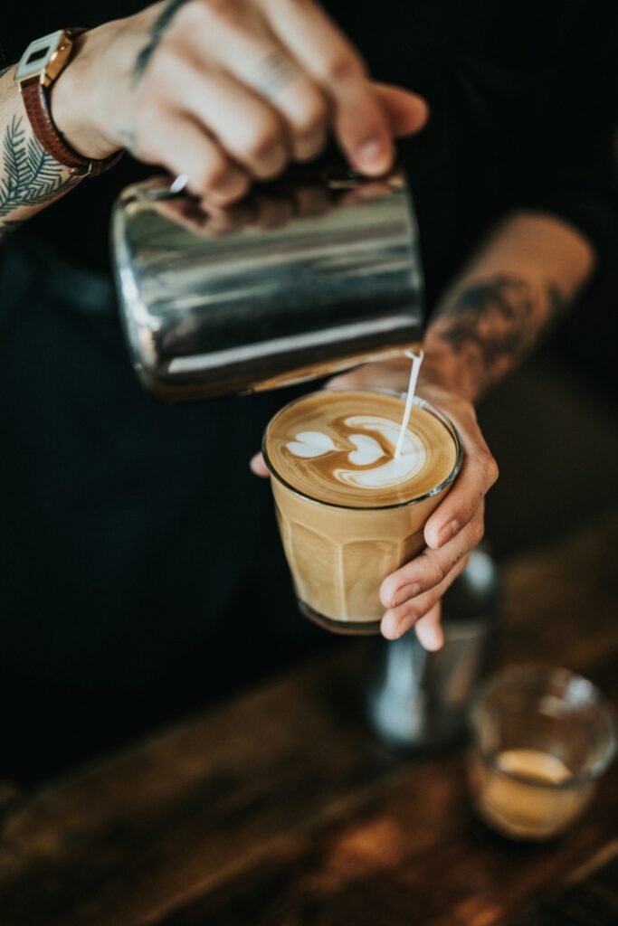 Persona vertiendo leche en una taza de caf&eacute;