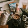 Persona sirviendo café de filtro recién hecho en una taza durante el desayuno