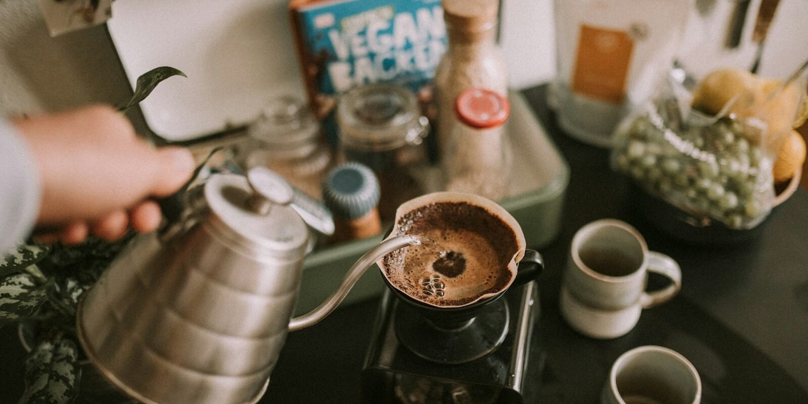 Persona sirviendo café de filtro recién hecho en una taza durante el desayuno