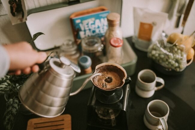 Persona sirviendo café de filtro recién hecho en una taza durante el desayuno