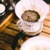 Jarra de cristal con café recién filtrado sobre una barra, con fondo desenfocado