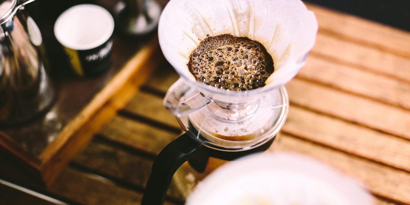 Jarra de cristal con café recién filtrado sobre una barra, con fondo desenfocado