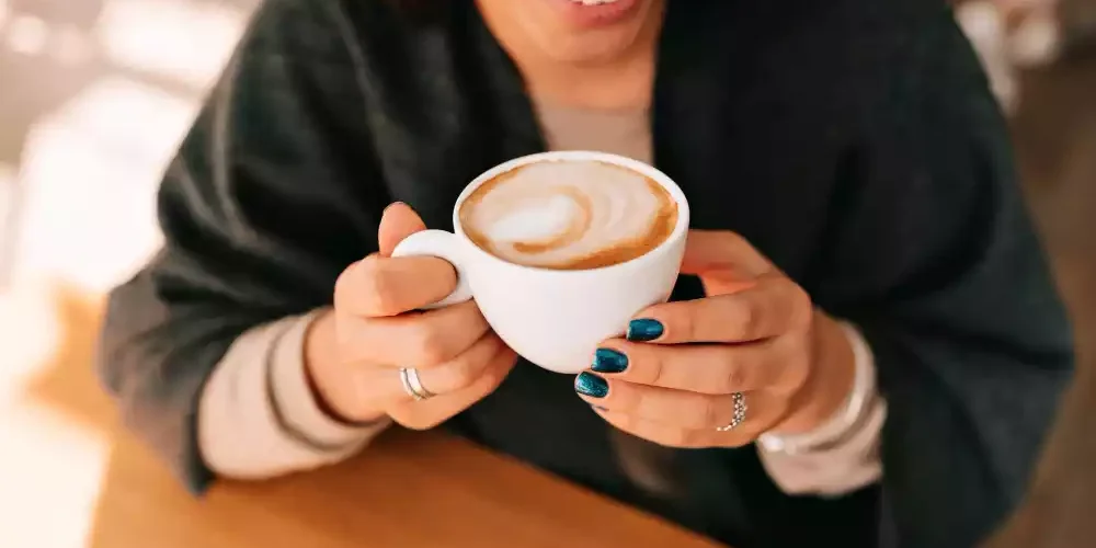 Una mujer bebiendo un capuccino