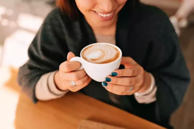 Una mujer bebiendo un capuccino