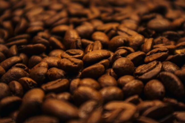 Granos de café tostado oscuro amontonados, donde se forman las melanoidinas que suavizan el amargor de la cafeína