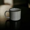 Taza de cerámica blanca con café solo sobre una superficie oscura