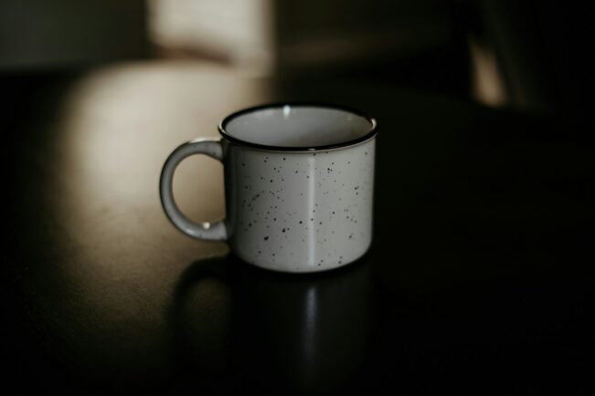 Taza de cerámica blanca con café solo sobre una superficie oscura