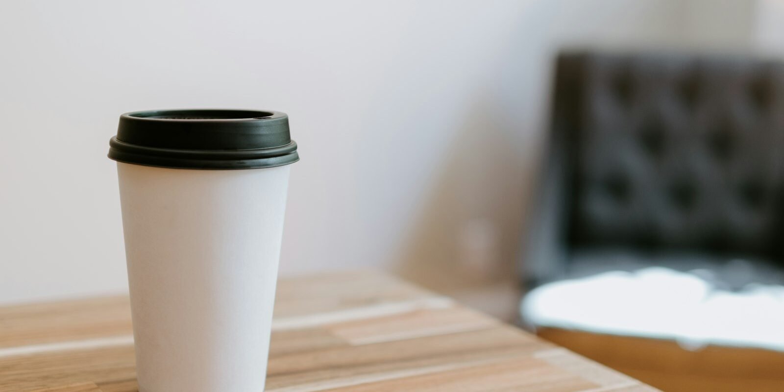 Vasos de papel para café: los «biodegradables» sueltan 12 veces más plástico Vaso de café desechable de papel blanco sobre una mesa de madera