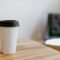 Vaso de café desechable de papel blanco sobre una mesa de madera